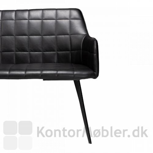 Embrace Sofa med polstring i sort kunstlæder. Den har koniske, lidt spinkle ben i sort metal, som giver en god kontrast designet på sædet